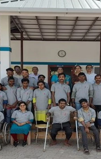 Group photo of staff and youth with disabilities outside a building at IOCL Kerala, with some individuals seated in wheelchairs and others standing, all smiling. Group photo of staff and youth with disabilities outside a building at IOCL Kerala, with some individuals seated in wheelchairs and others standing, all smiling.